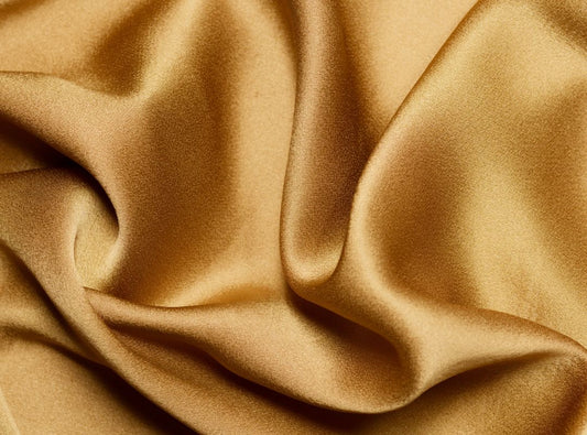 There is a golden camel colored shiny fabric pooled.