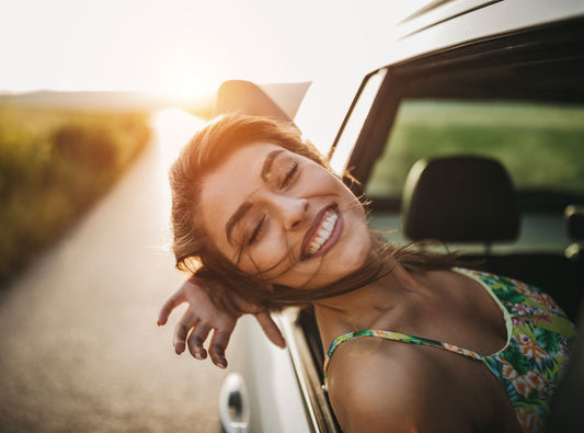 There is a woman leaning out of a car smiling.