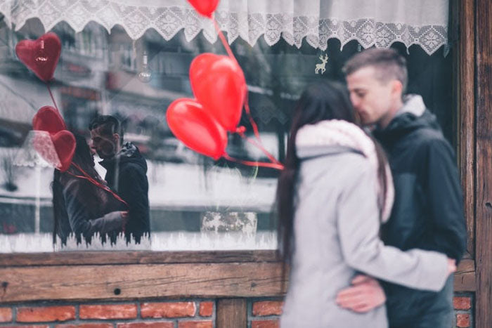 a couple with heart-shaped balloons sharing a kiss